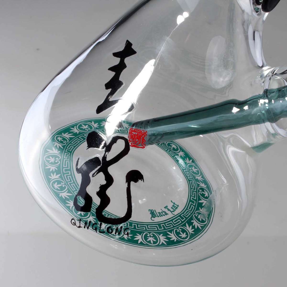 Clear glass bong with black calligraphy and green decorative border on a white background